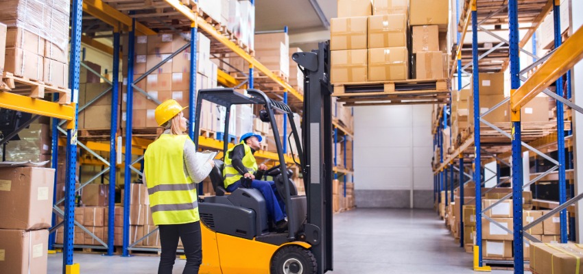 conducteur de chariot élévateur qui transporte palette sous la supervision d'une collègue