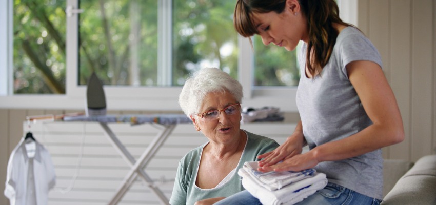 aide-ménagère sociale accompagnée d'une personne âgée. Elle plie le linge. 