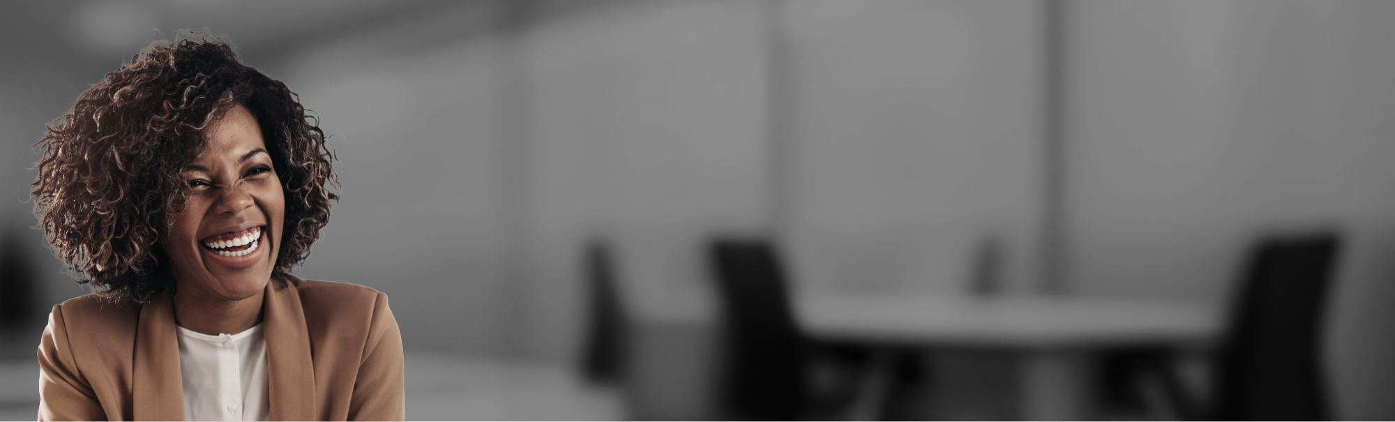 photo d'une dame avec un blazer marron et une chemise blanche. Elle sourit.